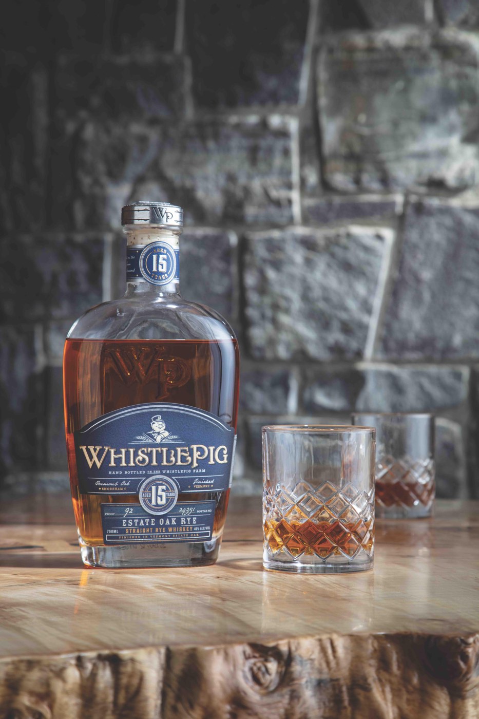 WhistlePig 15 Year Estate Oak Rye bottle beside a glass on a wooden table